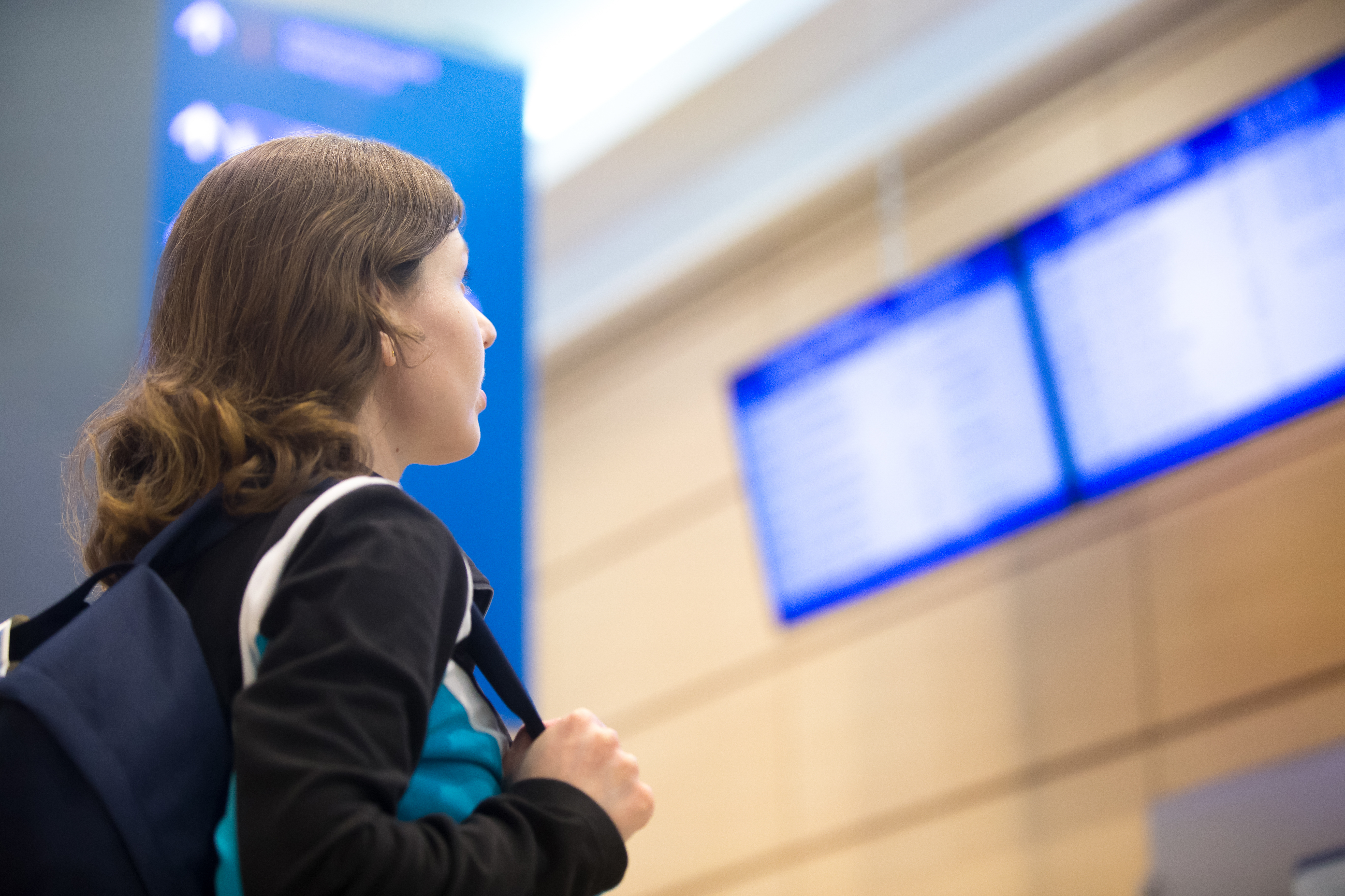 Girl looking at airport flight information board